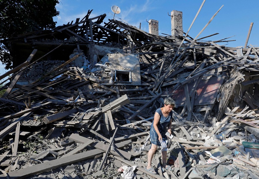 A person picks through the rubble of a destroyed house.