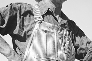 A black-and-white photograph of a man in striped overalls