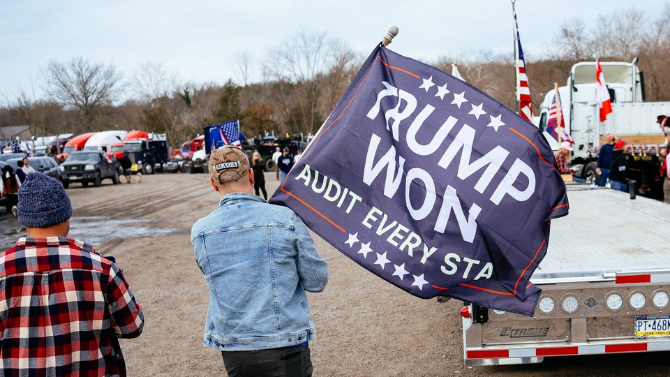 Man carrying a flag that says "Trump Won: Audit Every State."