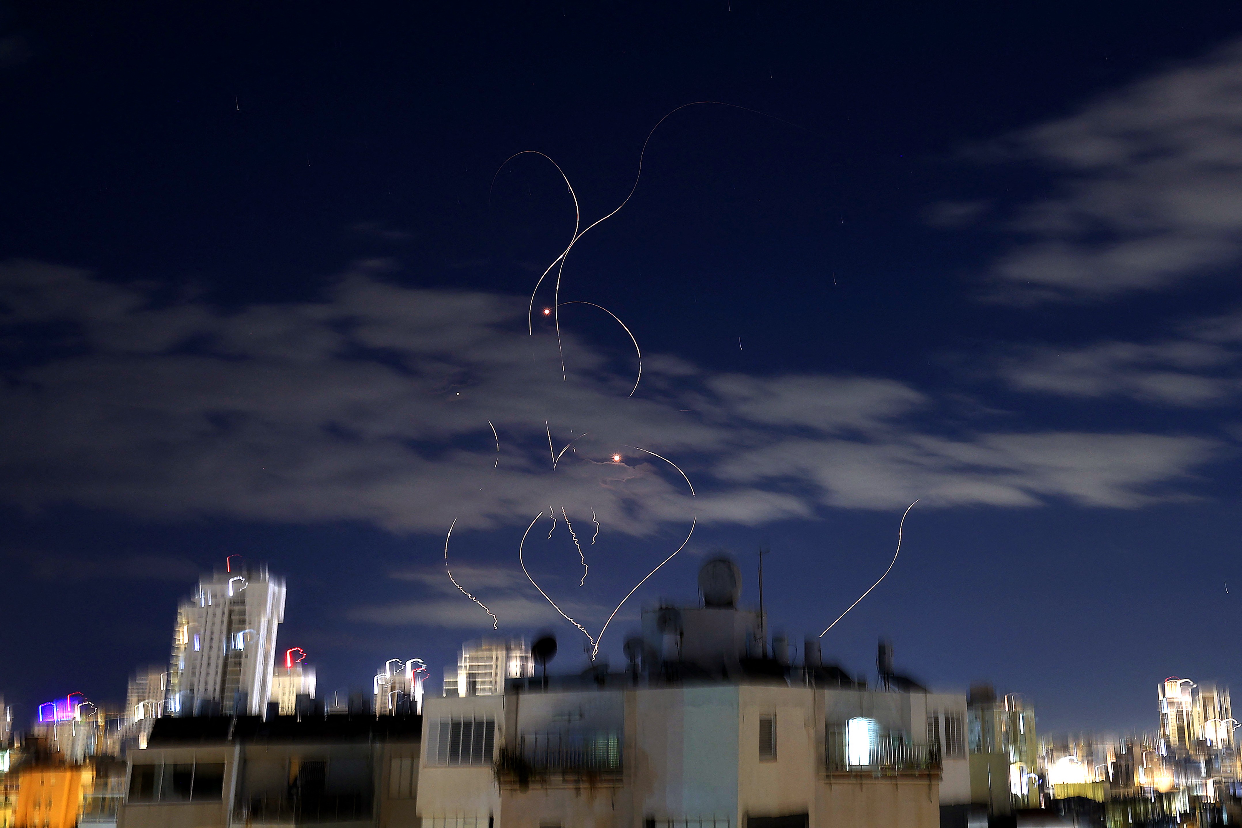 Rocket trails are seen in the sky above an Israeli city at night.