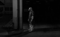 A person in a protective suit stands in the dark.