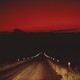 A photograph of a road going into Big Bend National Park during near dark, under a red sky