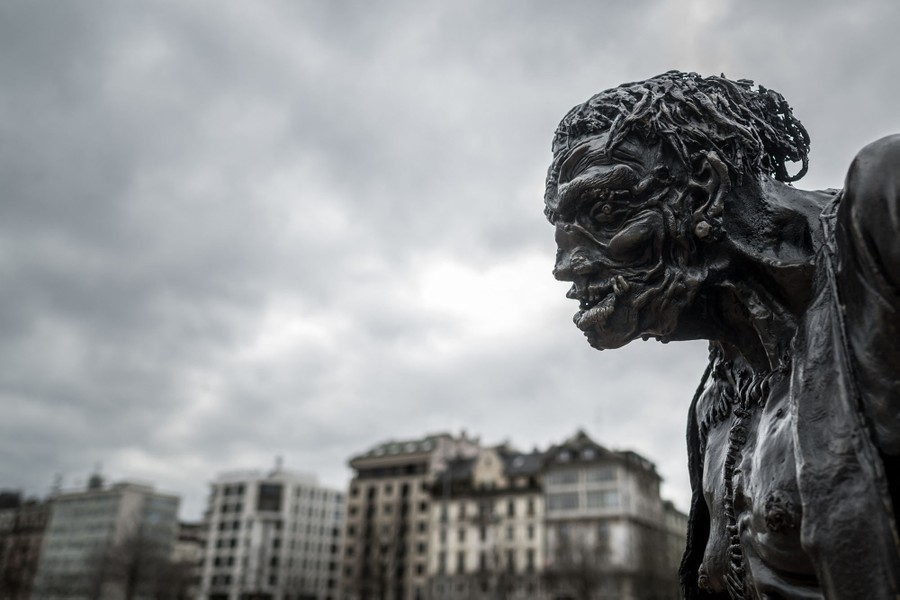 A close view of a metal statue of Frankenstein's monster in a city square.