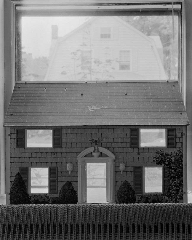 a doll house in front of a window showing another house