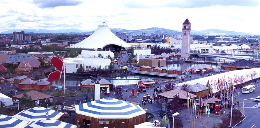 An overview of a fairground, featuring a tall, tent-shaped pavilion and a clock tower
