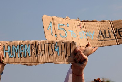 An image of a protest sign that reads "1.5 degrees to stay alive."