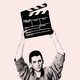 A photo of John Cusack holding a clapperboard above his head