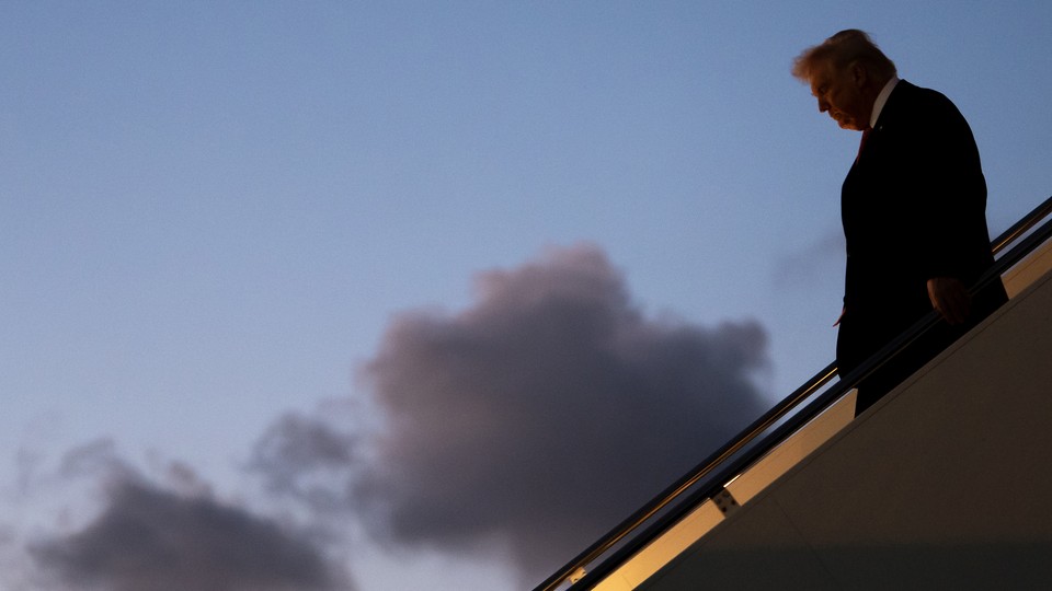 Color photograph of Trump walking down the stairs on Air Force One.