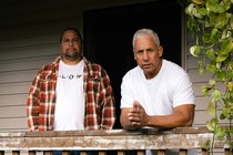 two men stand on a porch