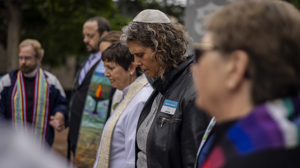 A row of Jews, one wearing a kippah, pray as they mourn the Boulder attack