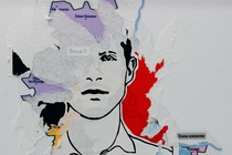 A photo of a half-torn sticker showing a portrait of Quentin Deranque