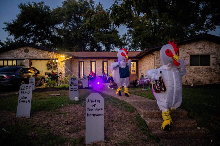 Trick-or-treaters dressed as chickens run down a house's front walk.