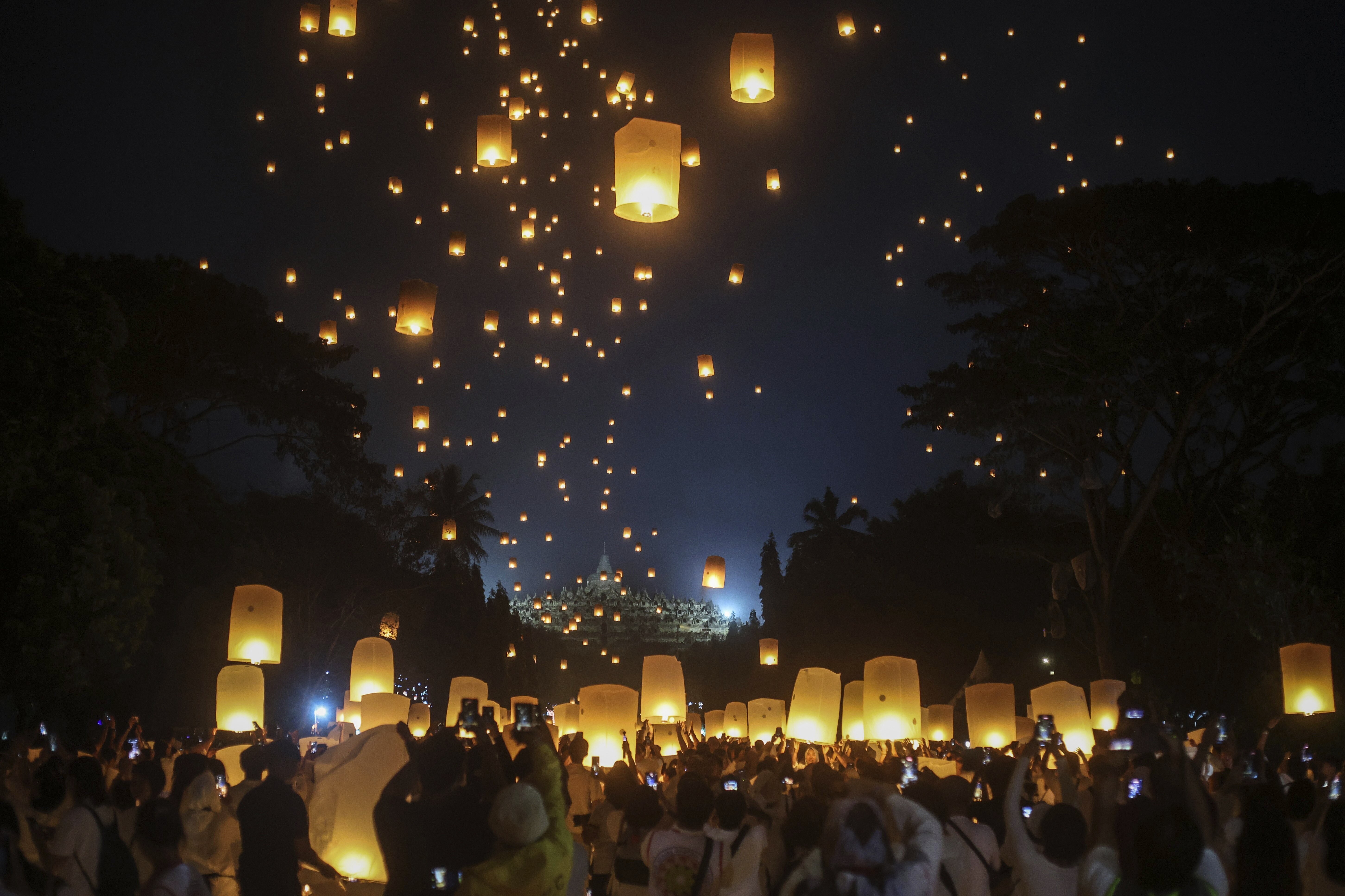 A crowd of people release hundreds of sky lanterns.