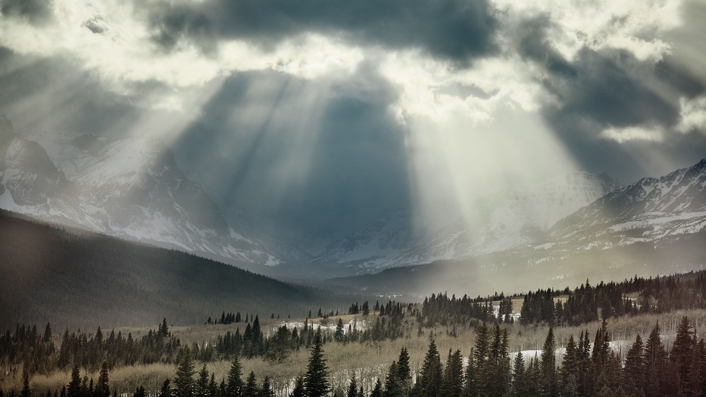 photo of Glacier National Park, Montana, with light streaming through clouds