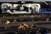 A train moves past rails surrounded by flames.