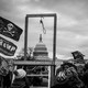 A crowd of Trump supporters surround a newly erected set of wooden gallows outside the Capitol Building.