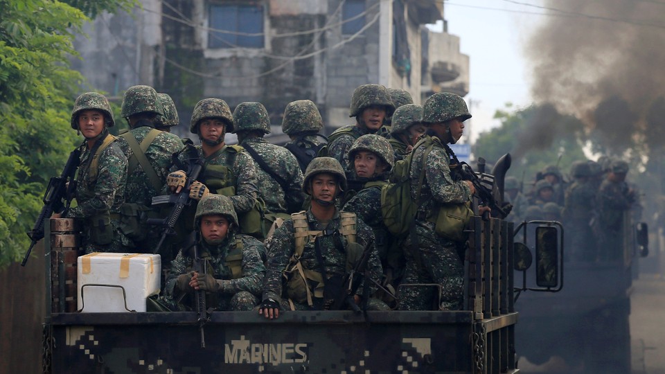 Soldiers onboard military trucks ride along the main street as government troops continue their assault on insurgents from the Maute group, who have taken over large parts of Marawi City, Philippines.
