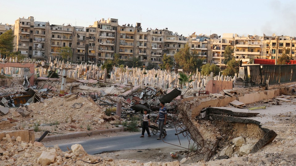 People walk near an over-crowded graveyard in the rebel-held al-Shaar neighborhood of Aleppo, Syria.