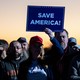 Supporters of Donald Trump hold up a sign at a "Save America" rally.