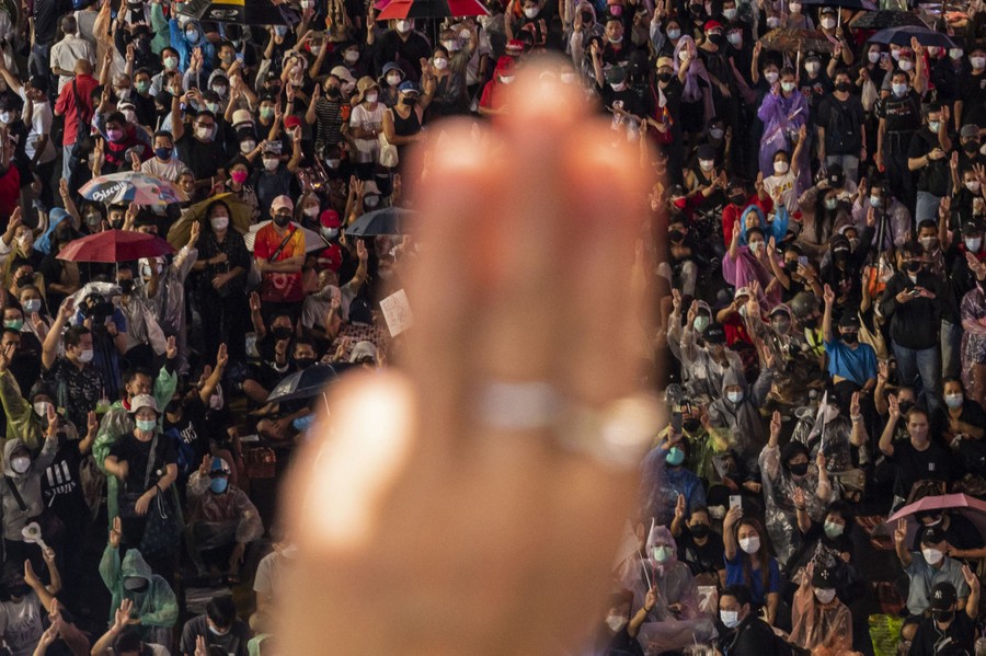 One blurry hand is seen close in the foreground, with dozens of protesters in the background.
