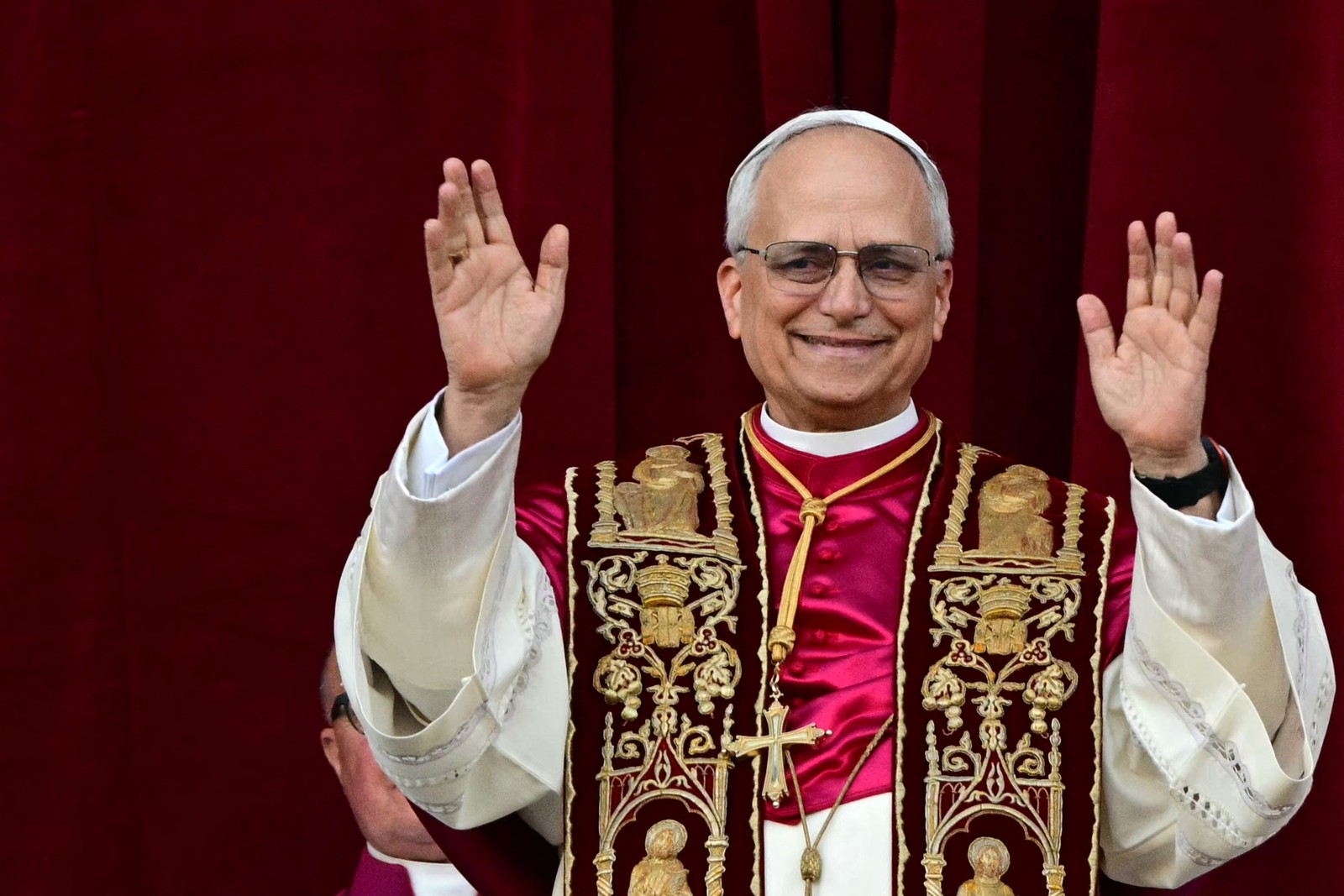Newly-elected Pope Leo XIV raises his hands, greeting a crowd from a balcony.