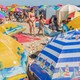Umbrellas on a beach, with beachgoers strolling around them