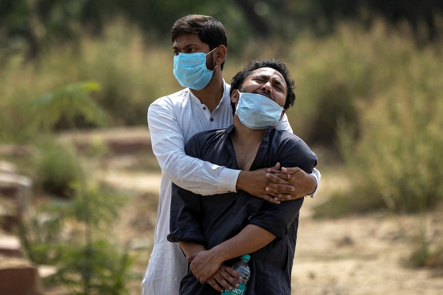 A man is consoled by his relative as he sees the body of his father.