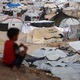 A child sits near tents