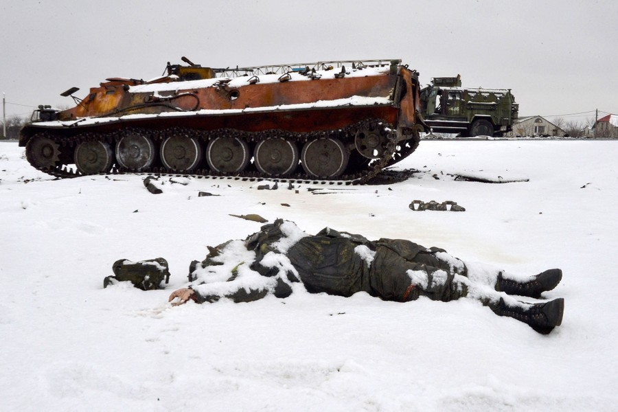 The body of a Russian serviceman lies in the snow near destroyed Russian military vehicles.