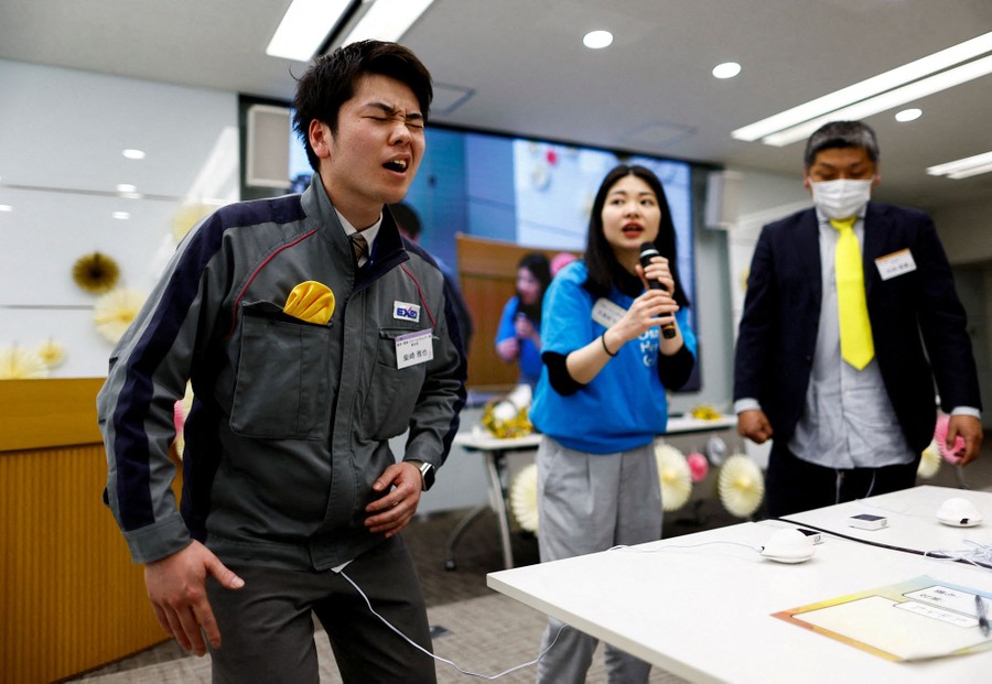 A man winces as electrical signals are sent via a wire under his jacket to a device on his belly that simulates women's menstrual pain.