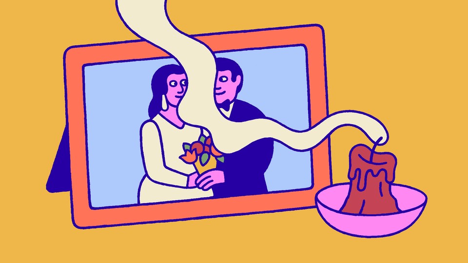 A photograph of a couple at their wedding with a candle in the foreground, the flame snuffed out