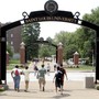 Students walk under an arch reading "Saint Louis University"
