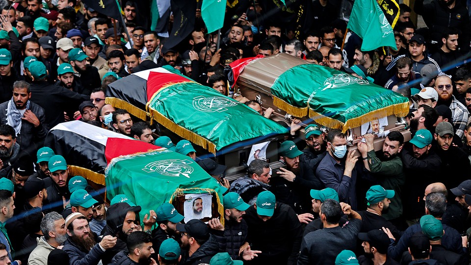 A crowd bears up Palestinian-flag-draped coffins at the funeral of Saleh al-Arouri