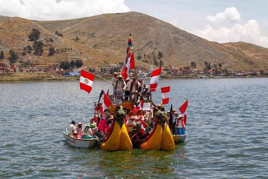 Protesters ride on several boats, waving flags.