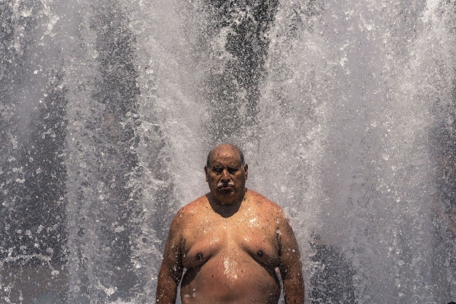 A shirtless man stands in a large fountain.