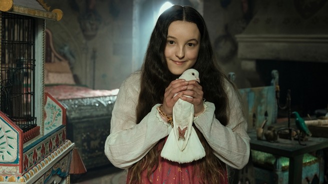 A young girl smiling and holding a bird in "Catherine Called Birdy"