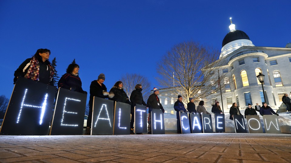 Holding signs, members of a pro-Medicaid group stage a rally outside a government building in Maine.