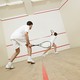 Two people wearing all-white playing squash together