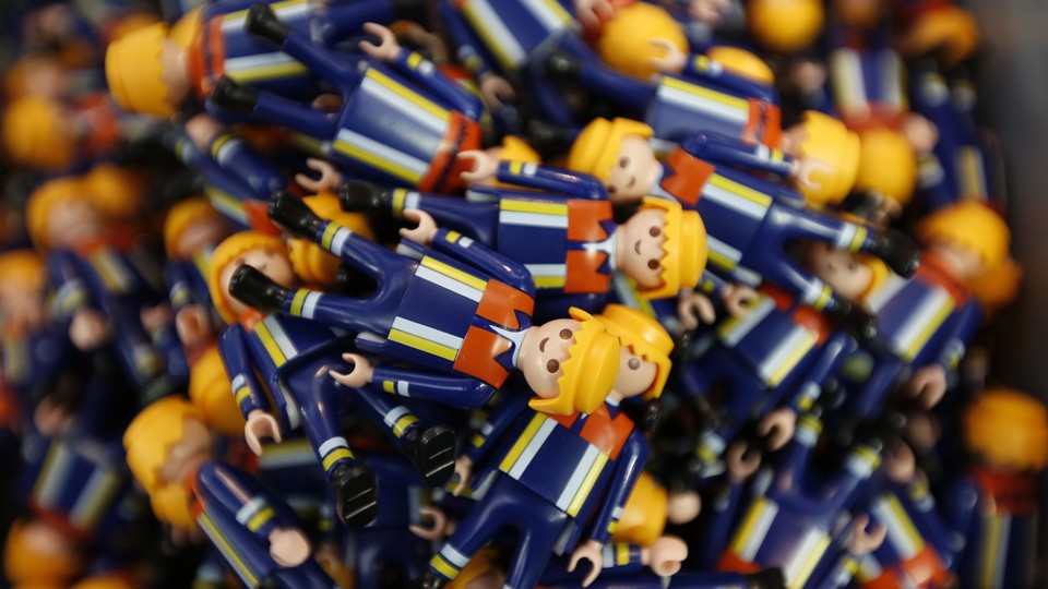 A sea of Playmobil figurines dressed in navy blue suits fills the frame.