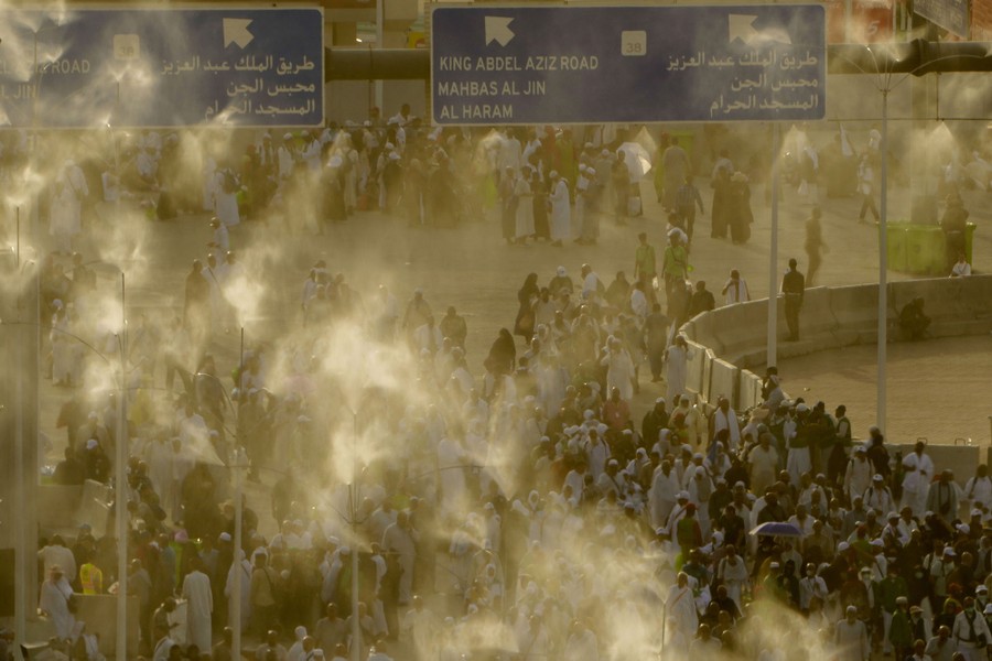 Misted water is sprayed on a crowd of people walking together.