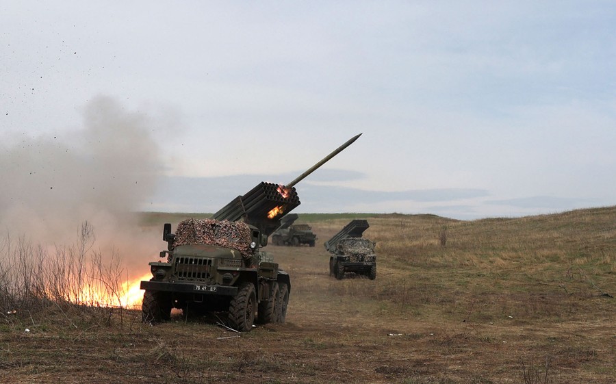 A rocket is fired from a military truck carrying a rocket launcher in a field.