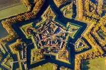 An aerial view of a small village built within the walls of a star-shaped fortress surrounded by a moat