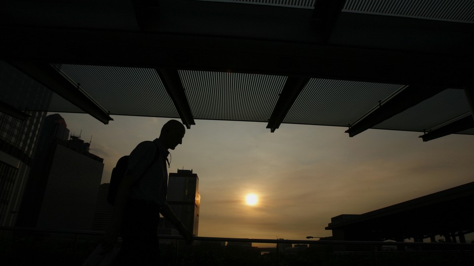 An expatriate business worker leaves an office building as the sun sets in Hong Kong's financial-business district on July 13, 2009.
