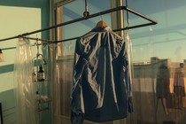 A shirt hanging in golden light before a big window showing a blue sky and a cityscape