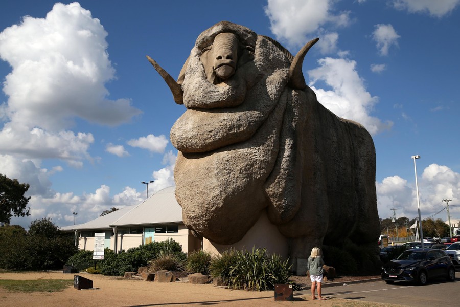 A giant concrete ram structure stands next to a smaller building.