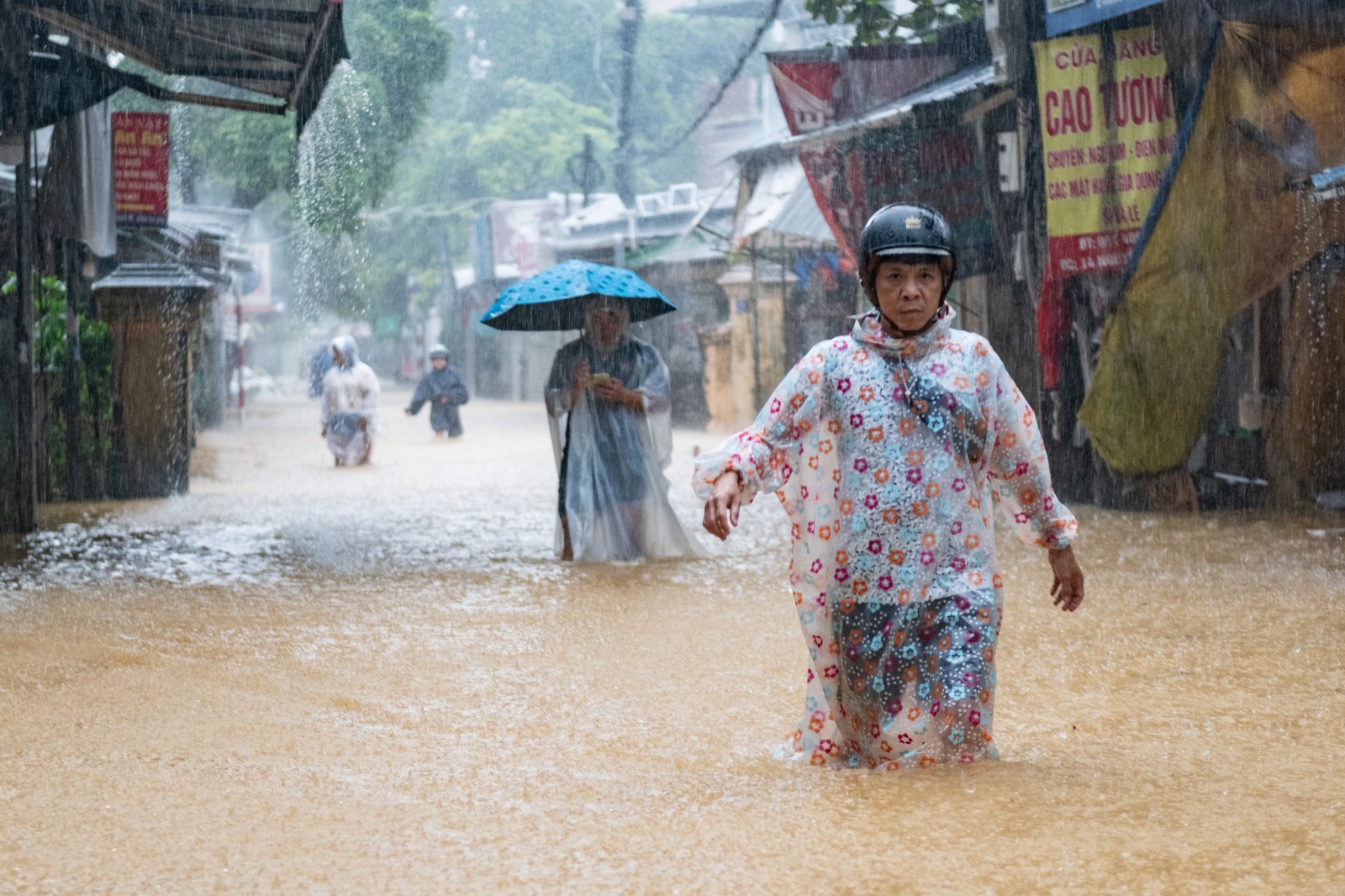 People wade through knee-deep floodwater.