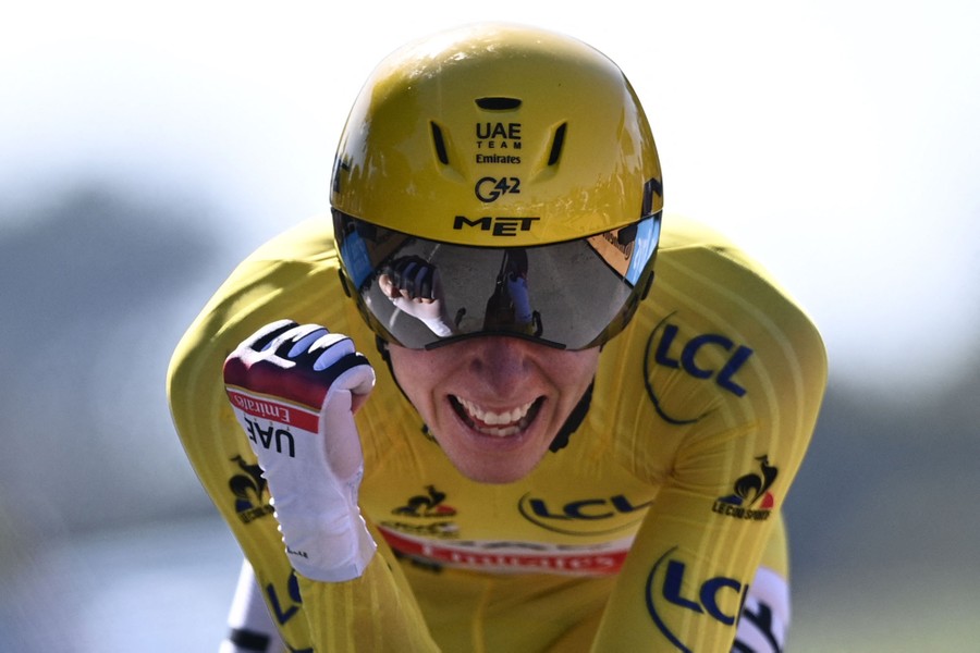 A yellow-jerseyed rider crosses a finish line.
