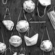 A black-and-white image of various N95 and surgical masks, hanging by their straps from pins on a wooden wall