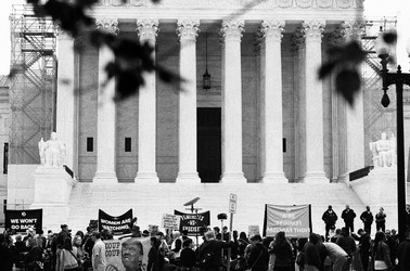 A black-and-white photo of protesters outside the entrance of the Supreme Court Building