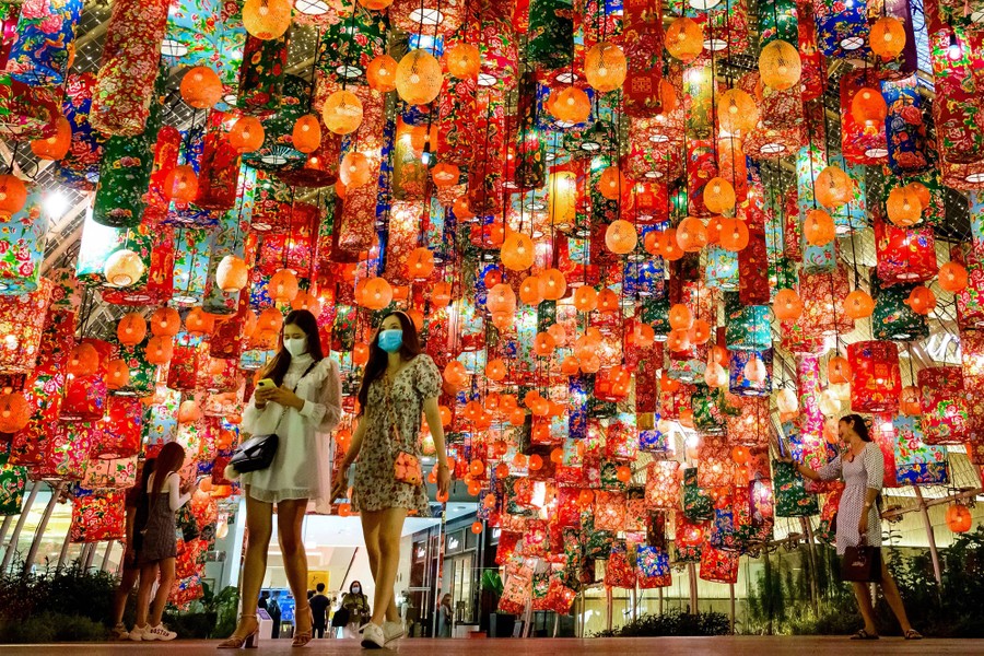 People walk beneath dozens of colorful lanterns.